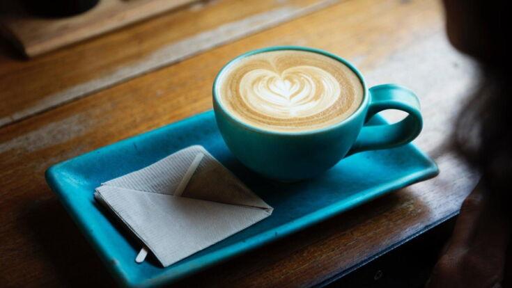 Tasse Kaffee wird mit Serviette auf Unterteller serviert