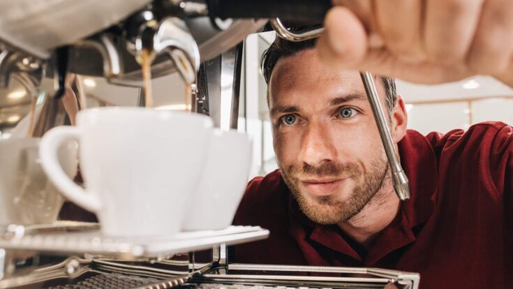Ein Techniker von Kaffee Partner beobachtet wie zwei Tassen Kaffee zubereitet werden