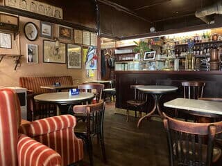 Café Hawelka mit Bar, Marmortischen und Bildern an der Wand