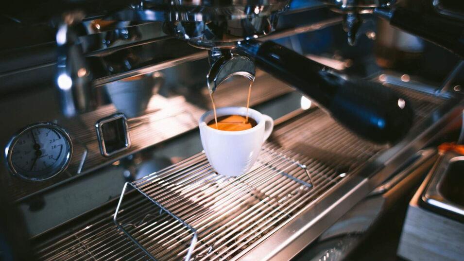 Espresso läuft aus silberner Siebträgermaschine in Espressotasse