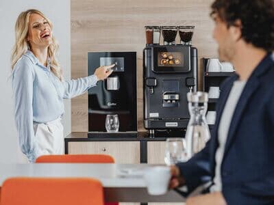 Frau zieht Wasser aus einem Wasserspender und lächelt