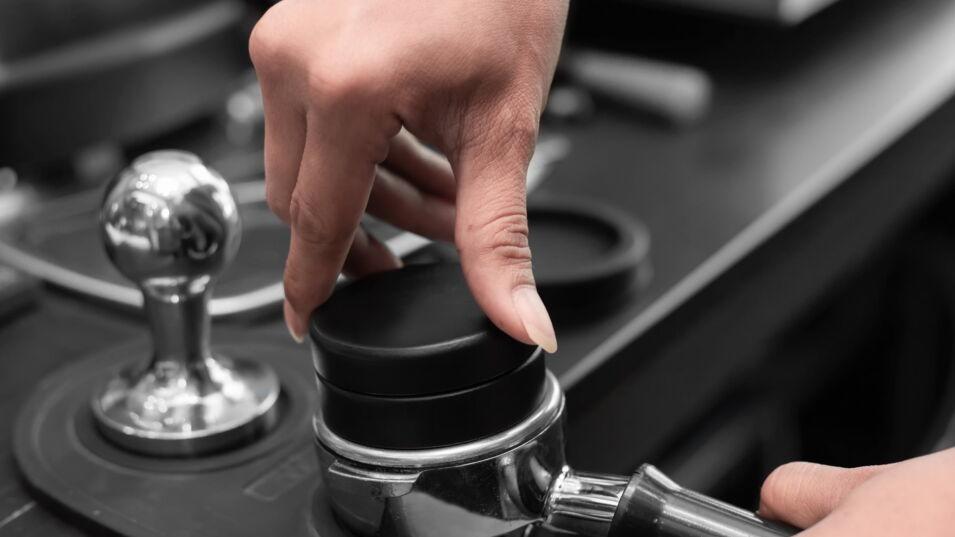 Barista benutzt einen Leveler beim Tamper