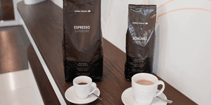 Zwei Kaffeepackungen von Kaffee Partner – Espresso Superiore und Schümli Gourmet – stehen nebeneinander auf einem dunklen Holztresen.