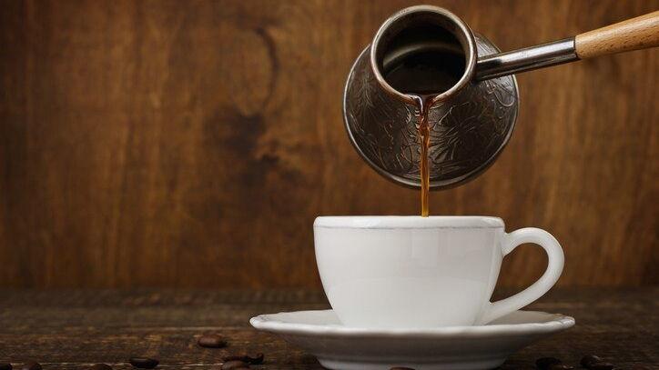 Dunkle Kaffee Tropfen aus einem Kupfer Ibrik in eine Tasse