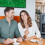 Mann-und-frau-mit-kaffee-am-tisch-vor-kaffeevollautomat