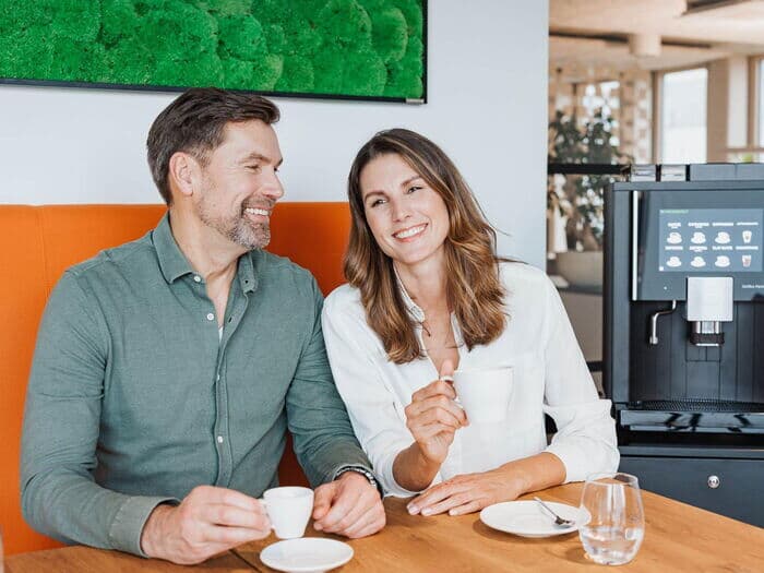 Mann-und-frau-mit-kaffee-am-tisch-vor-kaffeevollautomat