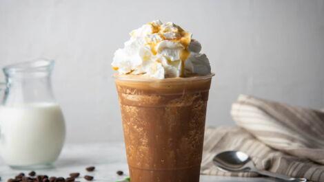 Frappuccino with cream on marble table Caramel frappuccino with whipped cream