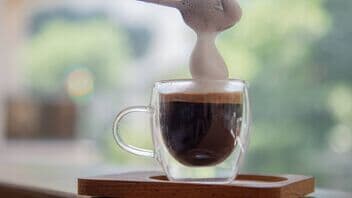 Glas mit Espresso und Milchschaum vor verschwommenem Hintergrund