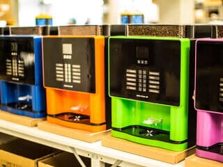 Produktionsreihe moderner Kaffeevollautomaten in Blau, Orange, Grün und Pink