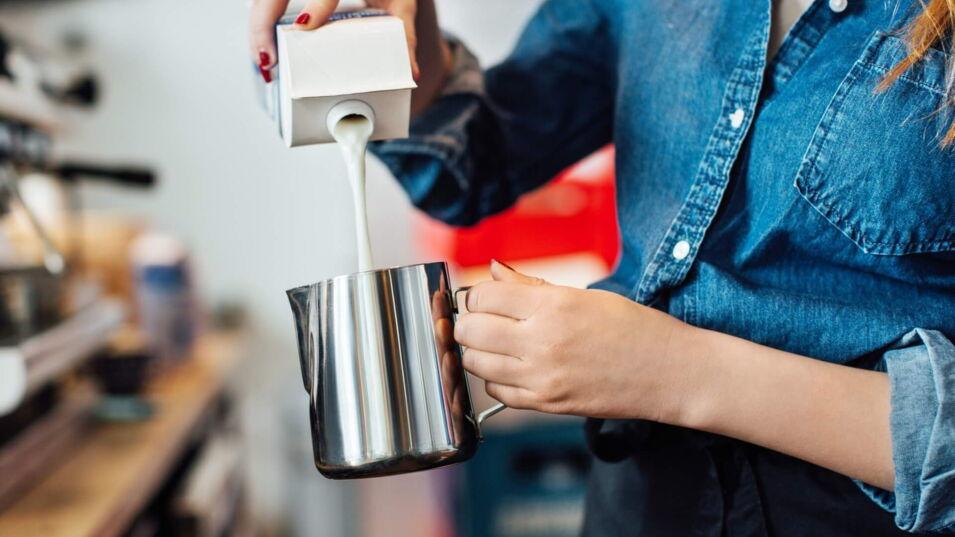 Barista gießt Milch in die Kanne