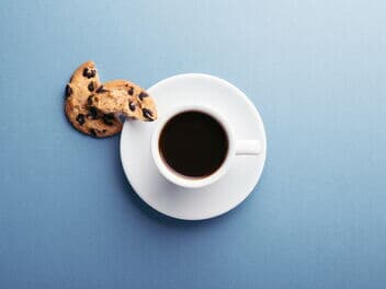 Schwarzer Kaffee serviert mit einem Cookie auf einer Untertasse