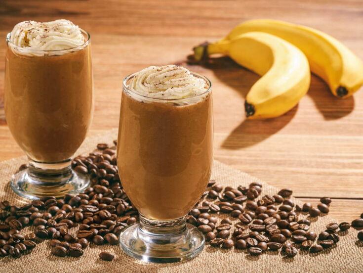Zwei Kaffees auf einem Tisch neben Bananen und Kaffeebohnen