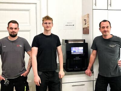 Drei Männer stehen neben einem gespendeten Kaffeevollautomaten des Typs multiBona3 von Kaffee Partner an die Osnabrücker Kindertafel