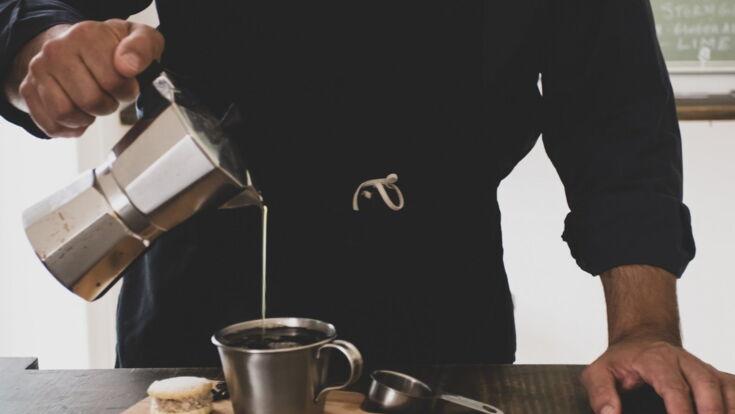 Mann schenkt Kaffee aus dem Espressokocher in eine Tasse