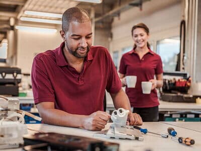 Kollege in der Fertigung bekommt einen Kaffee gebracht