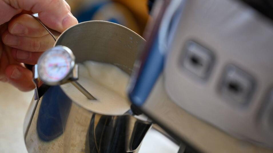 Milchschaum wird in kleiner Kanne zubereitet