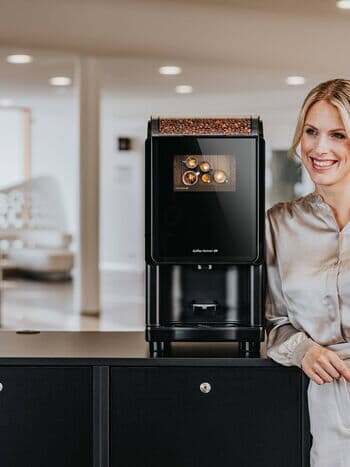 Frau neben Kaffeeautomaten-Modell Barista Compact