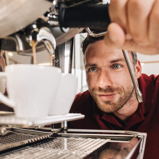 A technician from Kaffee Partner observes making two cups of coffee.