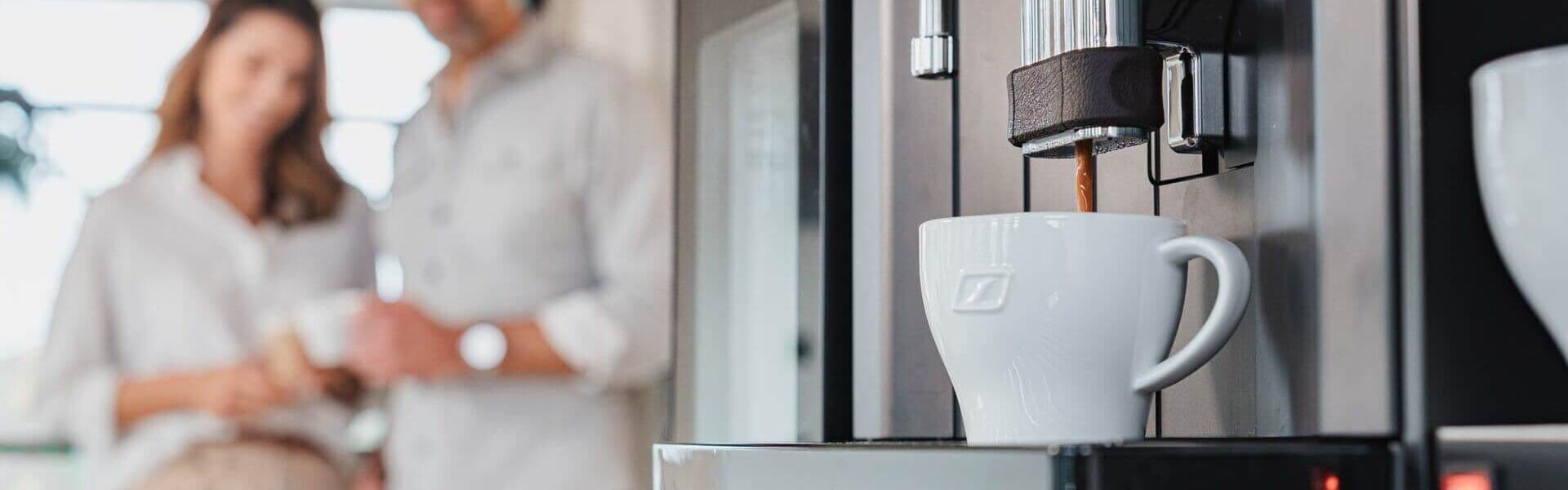 Frischer Kaffee läuft aus Kaffeevollautomat in eine weiße Tasse