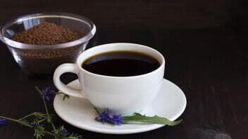 Weiße Tasse Zichorienkaffee mit Blüten und Schale Kaffeepulver