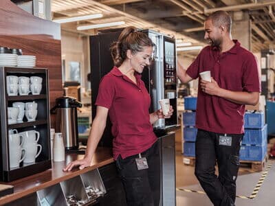 Zwei Mitarbeitende in der Fertigung genießen während einer kurzen Pause einen Kaffee aus der BARISTA Duro.