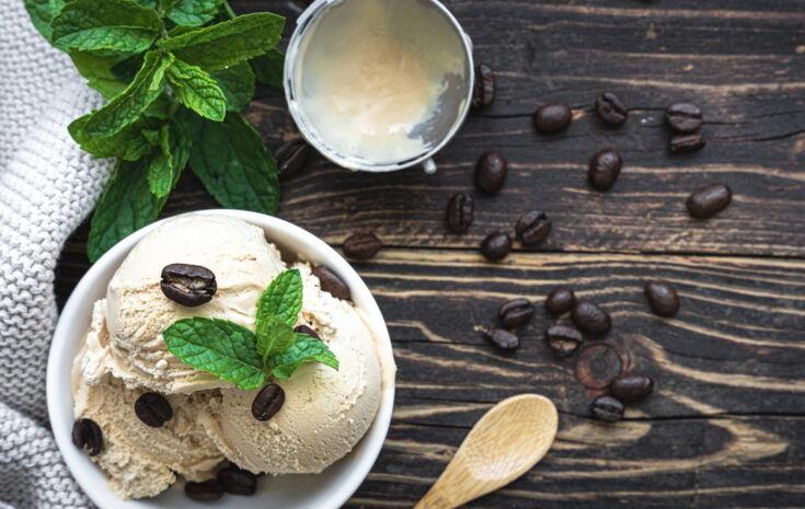 Eisbecher mit Kaffeebohnen auf einem Holztisch mit Holzlöffel