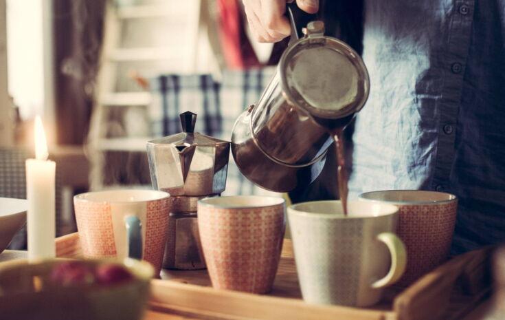 Kaffee wird aus einem Espressokocher in Tassen gegossen