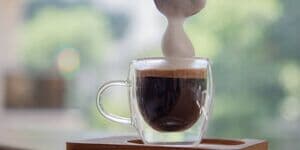 Glas mit Espresso und Milchschaum vor verschwommenem Hintergrund