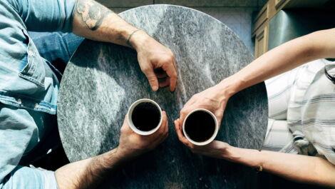 paar sitzt gegenueber und trinkt kaffee von oben
