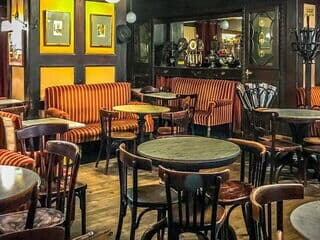 Café Hawelka mit runden Tischen und gestreiften Polstermöbeln in Wien