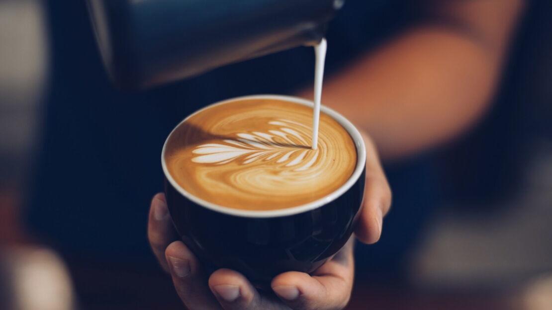 Barista verziert Cappuccino mit Latte Art