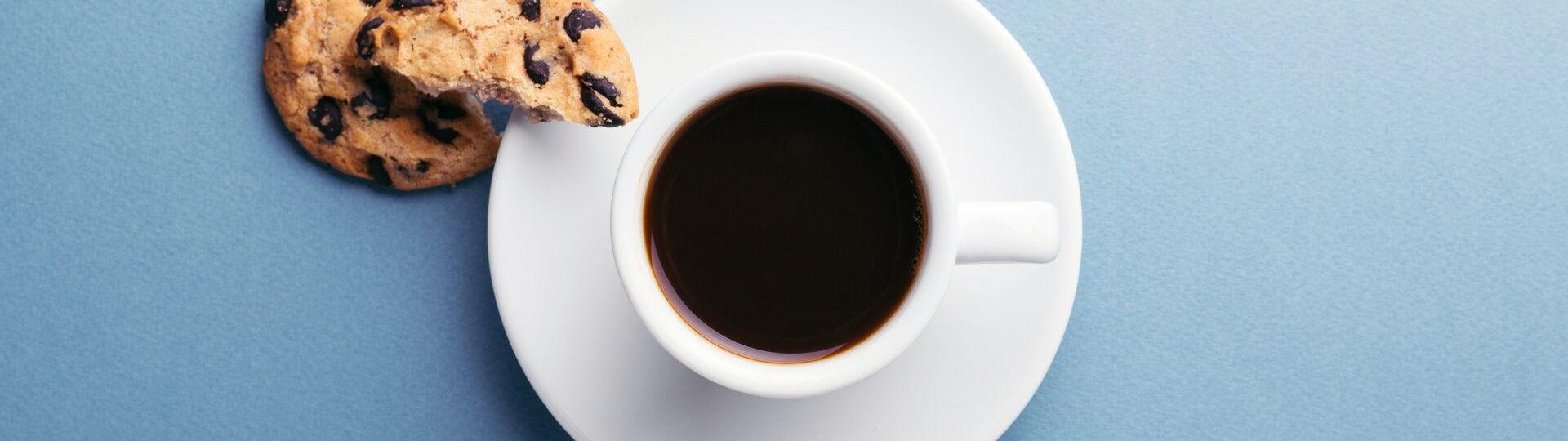 Schwarzer Kaffee serviert mit einem Cookie auf einer Untertasse