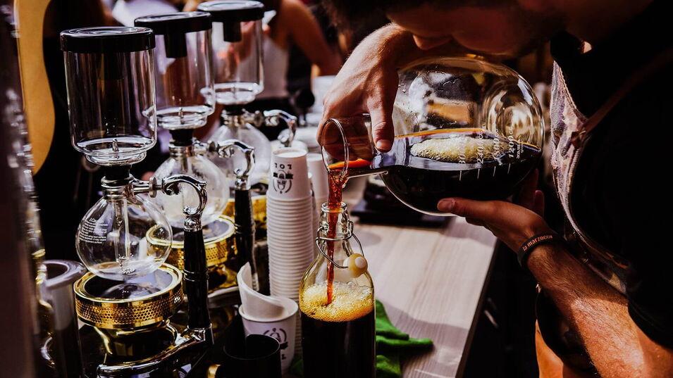 Ein Mann gießt Kaffee in ein Glas