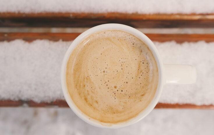 Kaffee mit Crema von oben auf einer verschneiten Parkbank