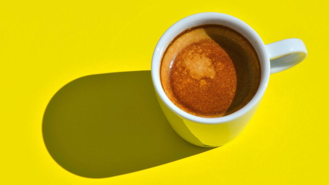 Eine Tasse Kaffee Crema steht auf gelbem Untergrund