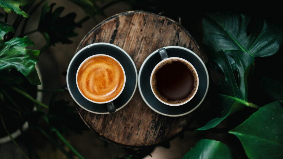 Blick von oben auf zwei Tassen – eine mit Kaffee Crema, die andere mit Filterkaffee gefüllt