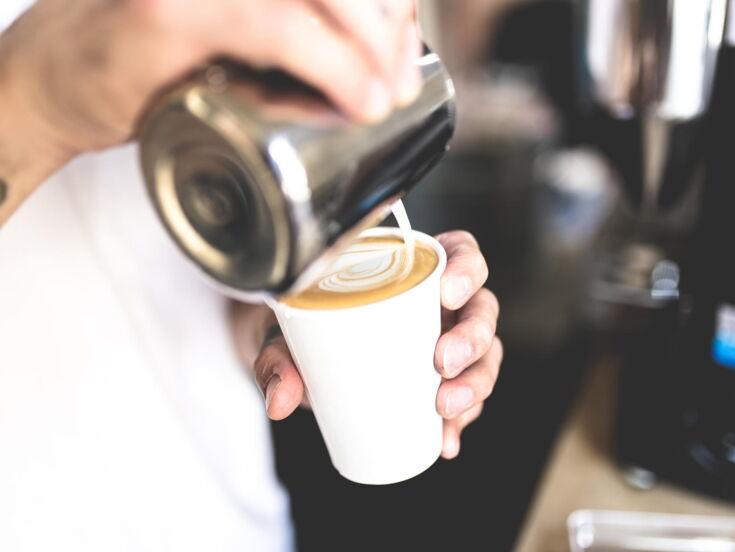 Mann macht Latte Art Herz in Becher