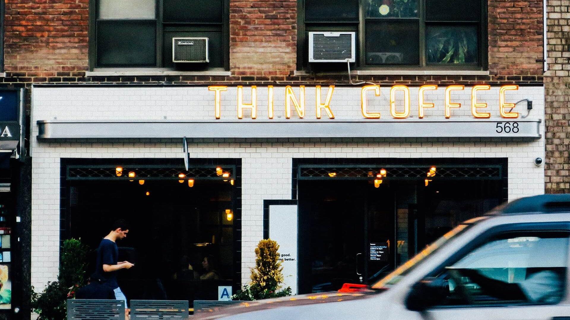 Cafe mit Leuchtreklame Think Coffee