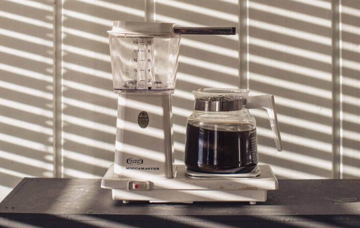 Filterkaffeemaschine Moccamaster auf einem Holztisch mit Schatten einer Jalousie
