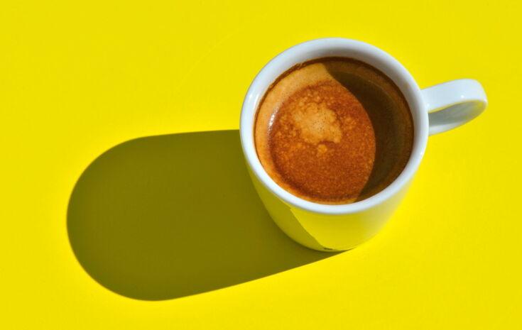 Eine Tasse Kaffee Crema steht auf gelbem Untergrund