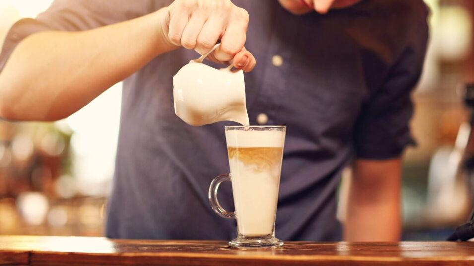 Mann gießt Espresso in Latte macchiato