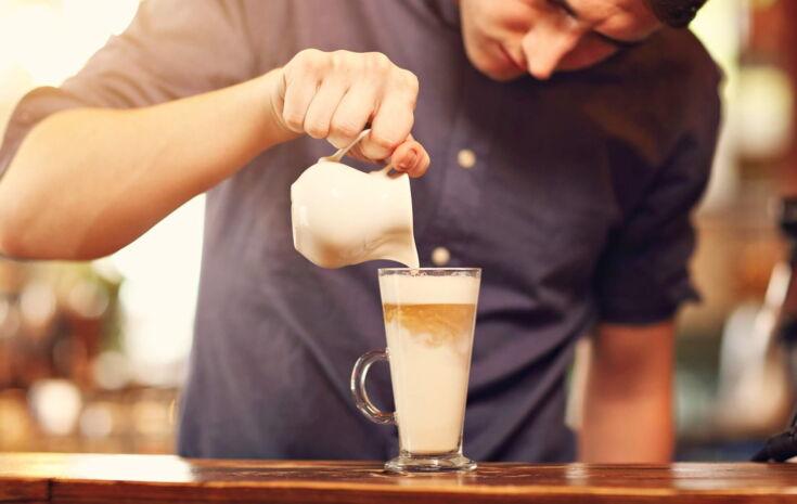 Mann gießt Espresso in Latte macchiato