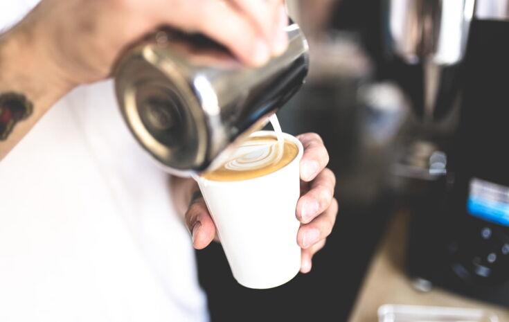 Mann macht Latte Art Herz in Becher
