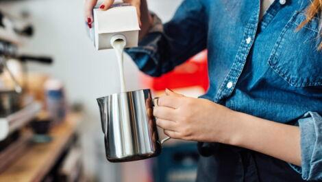 Barista gießt Milch in die Kanne