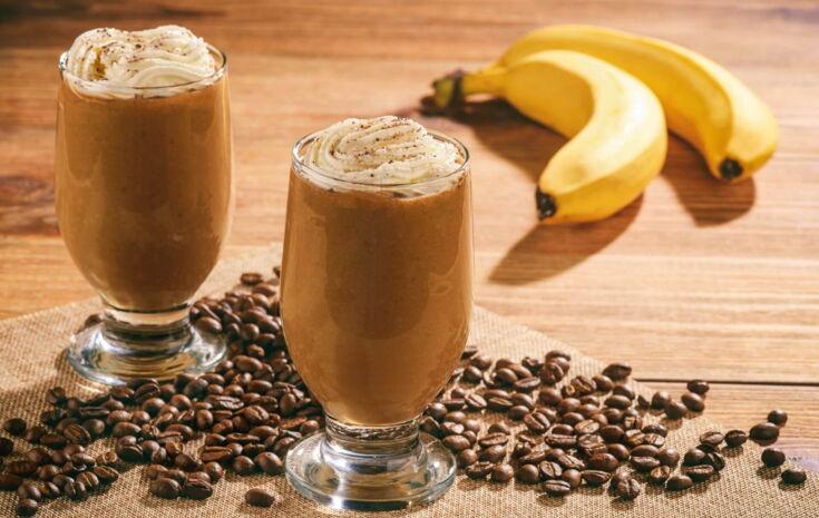 Zwei Kaffees auf einem Tisch neben Bananen und Kaffeebohnen