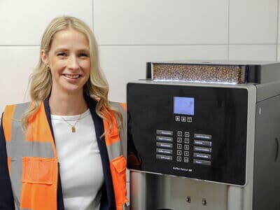 Mitarbeiterin von Bohnenkamp steht vor Kaffeemaschine