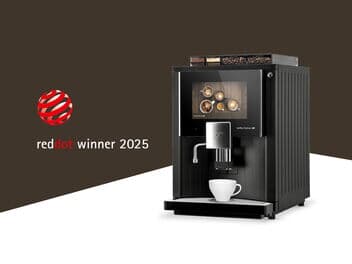 Kaffeevollautomat von Kaffee Partner mit moderner Touchscreen-Oberfläche, ausgezeichnet mit dem Red Dot Design Award 2025. Auf dem Bildschirm sind verschiedene Kaffeespezialitäten zu sehen. Links daneben das Red Dot Winner Logo auf braunem Hintergrund.