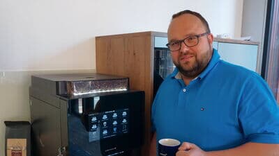 Dirk Fedder, Director Prodware Deutschland AG, steht vor Kaffeevollautomat multiBona 3