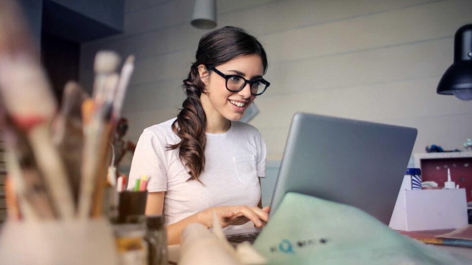 Laechelnde Frau arbeitet am Laptop