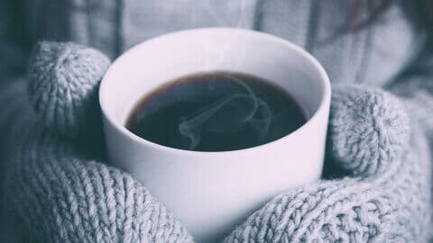 Eine Kaffeetasse in den Händen